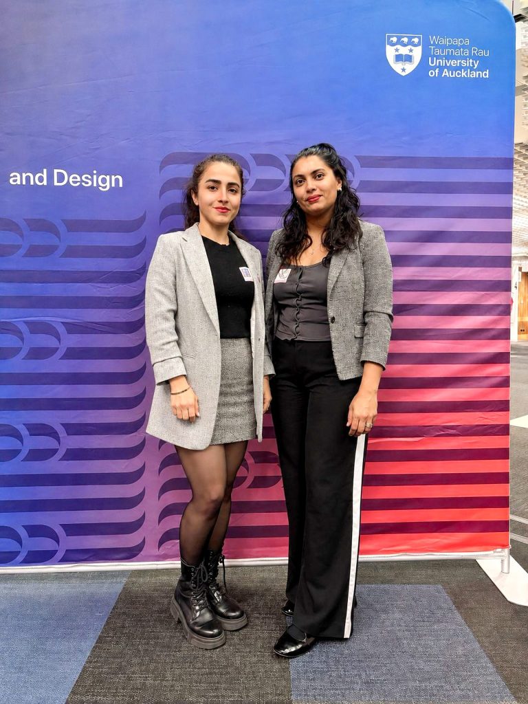 Maryam Hasanali and Ronita Kishore picture in from of University of Auckland display stand.